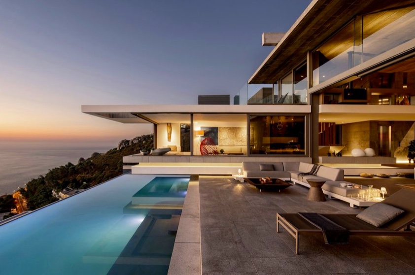 Villa mit Infinity-Pool in der Abenddämmerung über dem Meer